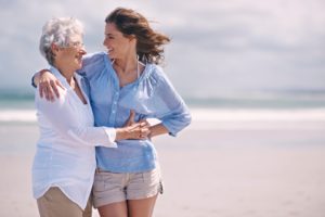 Senior woman hugging her adult daughter on a beach