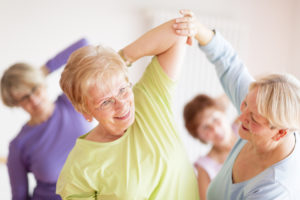 Older woman stretching with assistance from an instructor