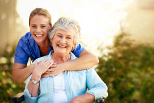 Caregiver and senior smiling into the camera outdoors