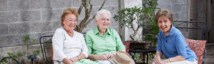 Three senior women sitting on a patio outdoors