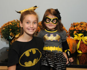 Superheroes get ready to canvas the neighborhood at Allerton House for delicious treats. Ella Botelho, age 2 and Maeve Duquette, age 10 are pleased to pose in their Batgirl costumes.