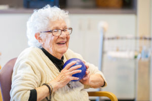 Smiling senior woman holding a purple ball